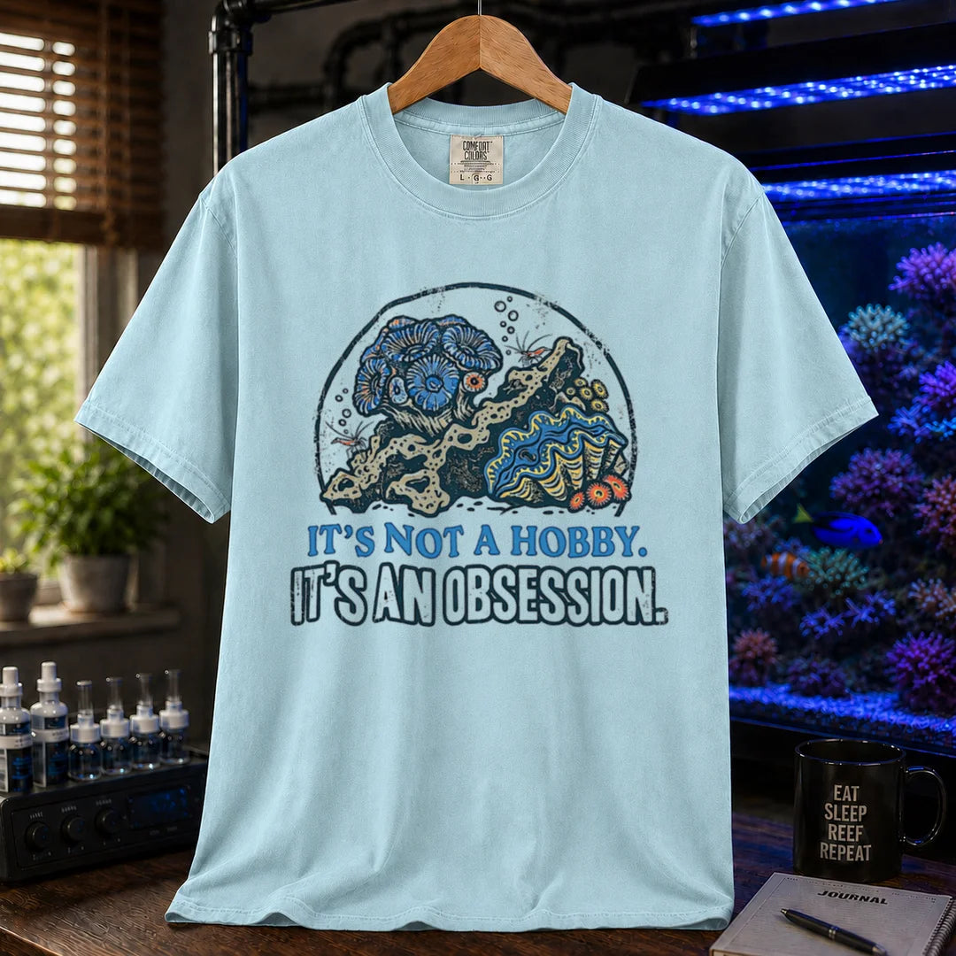 Saltwater aquarium graphic t-shirt featuring a reef aquascape illustration and text: IT'S NOT A HOBBY. IT'S AN OBSESSION., light blue crew neck tee