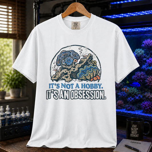 Saltwater aquarium graphic t-shirt featuring a reef aquascape illustration and text: IT'S NOT A HOBBY. IT'S AN OBSESSION., white crew neck tee