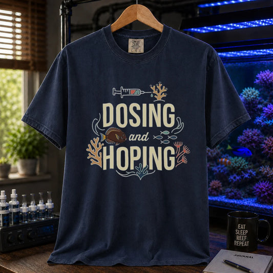 Saltwater aquarium graphic t-shirt featuring a dosing syringe and coral illustration with text: DOSING and HOPING, navy crew neck tee