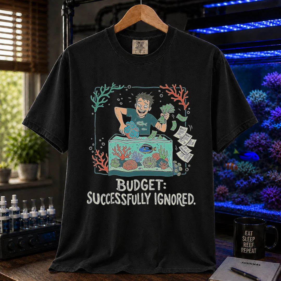 Saltwater aquarium graphic t-shirt featuring an aquarist tossing bills into a tank illustration with text: BUDGET: SUCCESSFULLY IGNORED., black crew neck tee
