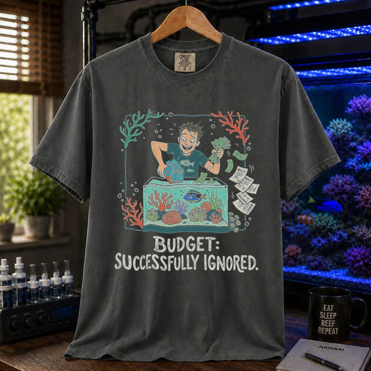 Saltwater aquarium graphic t-shirt featuring an aquarist tossing bills into a tank illustration with text: BUDGET: SUCCESSFULLY IGNORED., dark grey crew neck tee