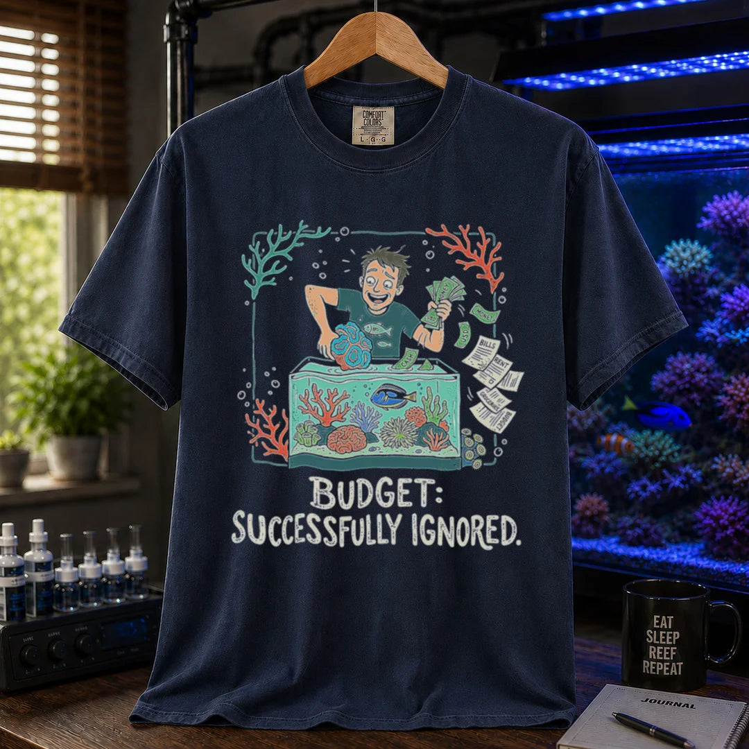 Saltwater aquarium graphic t-shirt featuring an aquarist tossing bills into a tank illustration with text: BUDGET: SUCCESSFULLY IGNORED., navy crew neck tee