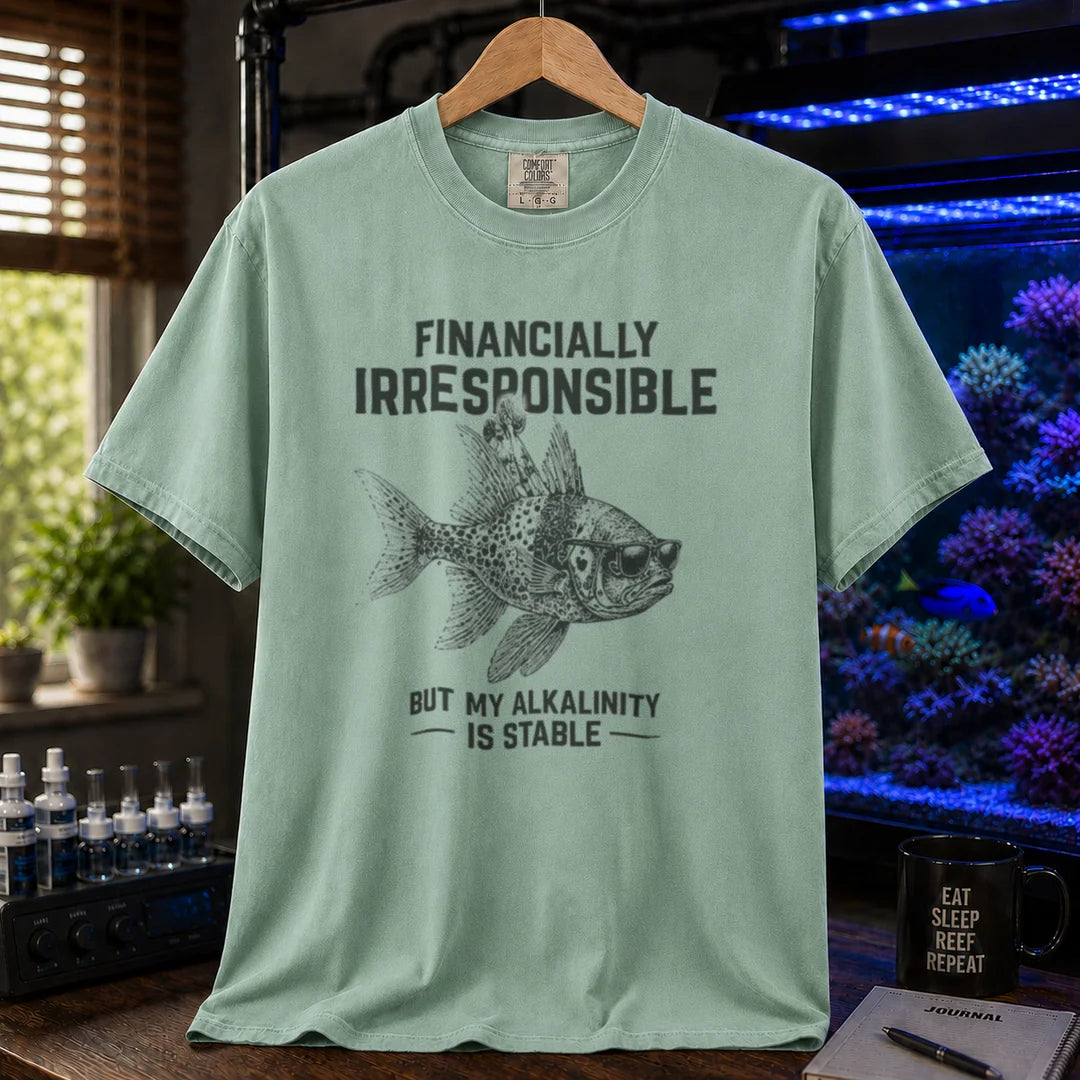 Saltwater aquarium graphic t-shirt featuring a fish in sunglasses illustration and text: FINANCIALLY IRRESPONSIBLE BUT MY ALKALINITY IS STABLE, green crew neck tee