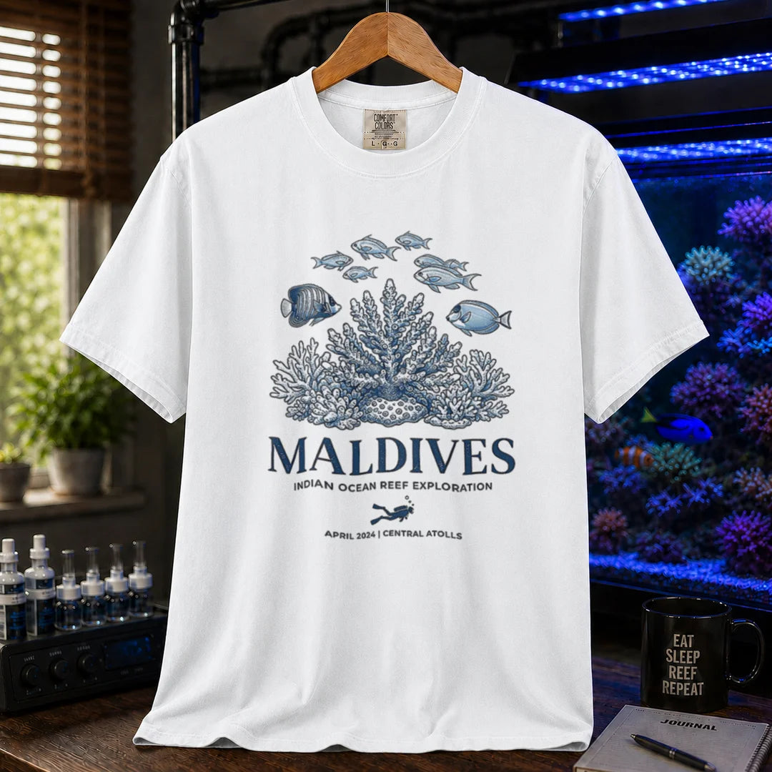 Saltwater aquarium graphic t-shirt featuring a coral reef and fish illustration with text: MALDIVES INDIAN OCEAN REEF EXPLORATION APRIL 2024 CENTRAL ATOLLS, white crew neck tee
