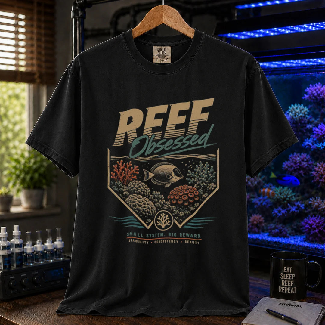 Saltwater aquarium graphic t-shirt featuring a retro coral emblem and text: REEF Obsessed SMALL SYSTEM. BIG REWARD. STABILITY . CONSISTENCY . BEAUTY, black crew neck tee