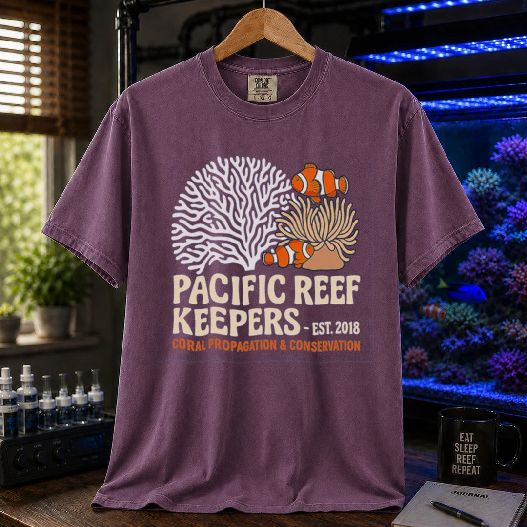 Saltwater aquarium graphic t-shirt featuring clownfish, anemone, and coral illustrations with text: PACIFIC REEF KEEPERS - EST. 2018 SUSTAINABLE REEFKEEPING, purple crew neck tee