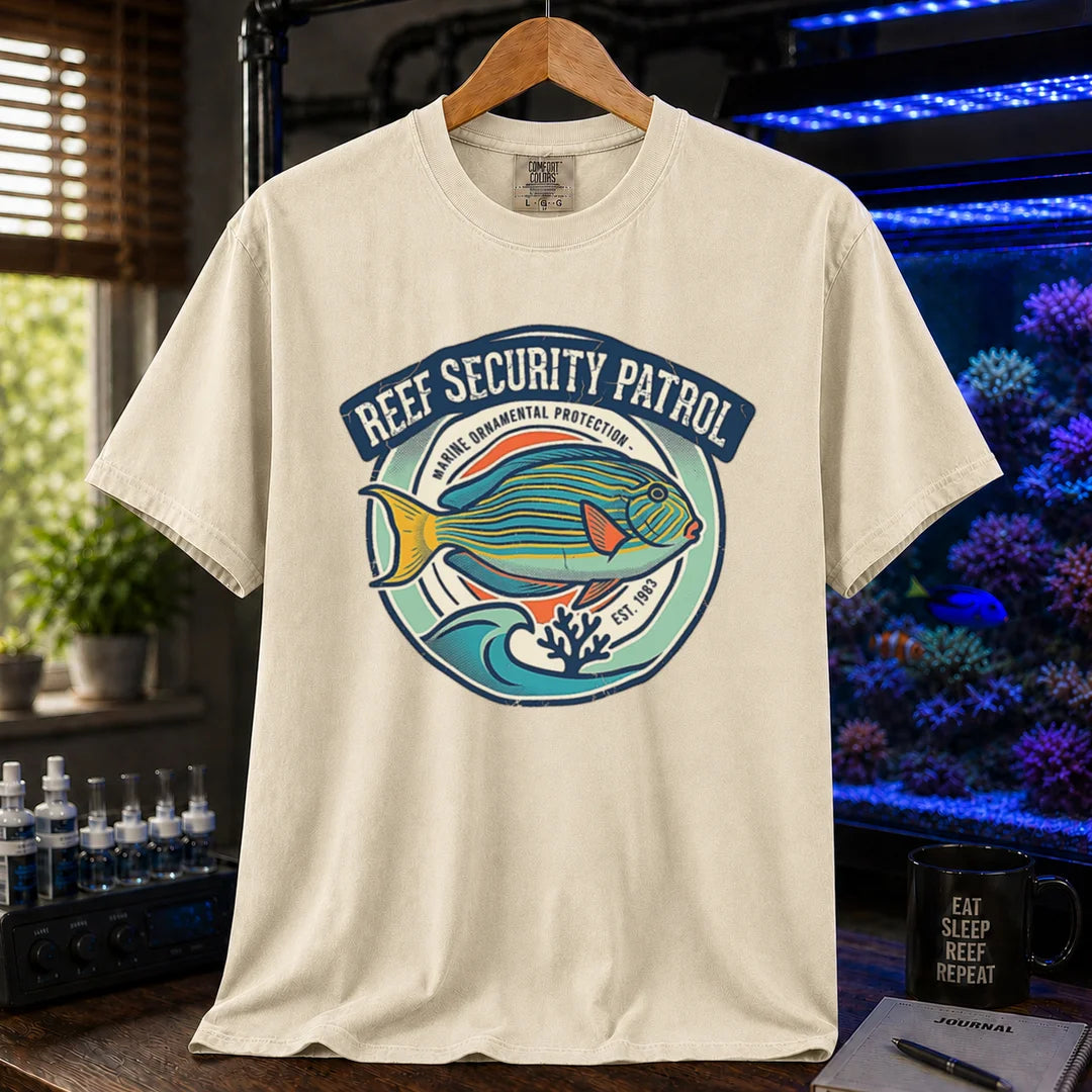 Saltwater aquarium graphic t-shirt featuring a circular emblem with a reef fish illustration and text: REEF SECURITY PATROL MARINE ORNAMENTAL PROTECTION EST. 1983, cream, beige, ivory crew neck tee
