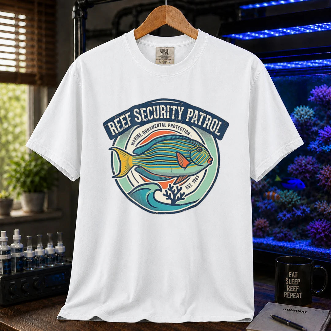 Saltwater aquarium graphic t-shirt featuring a circular emblem with a reef fish illustration and text: REEF SECURITY PATROL MARINE ORNAMENTAL PROTECTION EST. 1983, white crew neck tee
