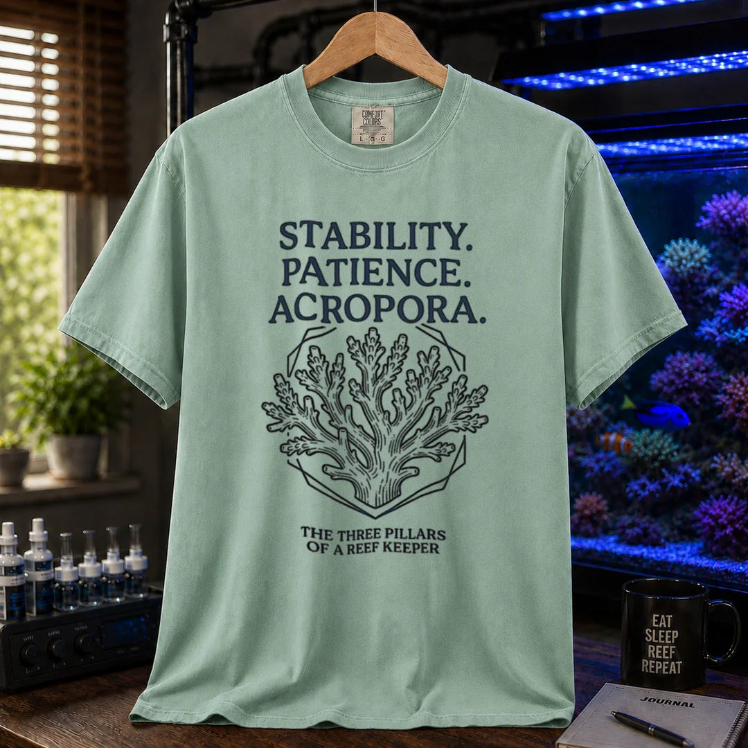 Saltwater aquarium graphic t-shirt featuring an Acropora coral illustration and text: STABILITY. PATIENCE. ACROPORA. THE THREE PILLARS OF A REEF KEEPER, green crew neck tee