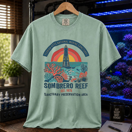 Saltwater aquarium graphic t-shirt featuring a lighthouse and coral reef illustration with text: FLORIDA KEYS NATIONAL MARINE SANCTUARY SOMBRERO REEF EST. 1975 SANCTUARY PRESERVATION AREA, green crew neck tee