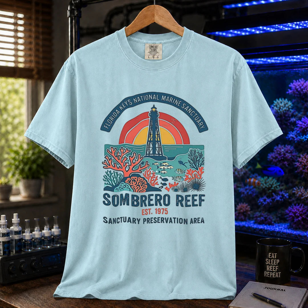Saltwater aquarium graphic t-shirt featuring a lighthouse and coral reef illustration with text: FLORIDA KEYS NATIONAL MARINE SANCTUARY SOMBRERO REEF EST. 1975 SANCTUARY PRESERVATION AREA, light blue crew neck tee