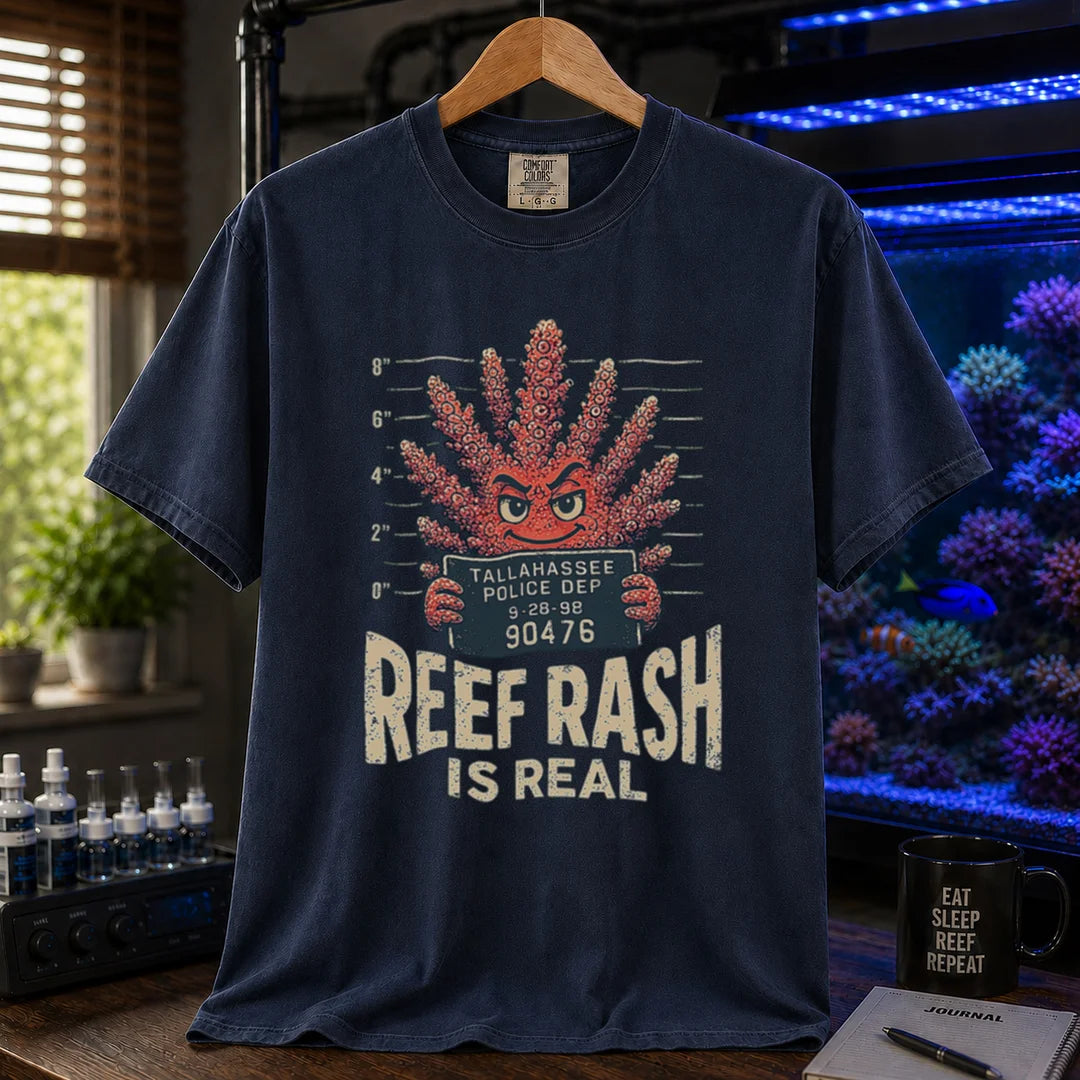 Saltwater aquarium graphic t-shirt featuring a mugshot of an anthropomorphic coral holding a police booking sign with text: REEF RASH IS REAL, navy crew neck tee