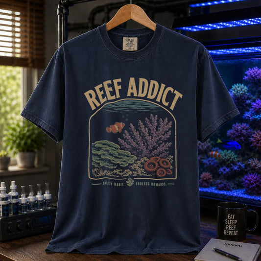 Saltwater aquarium graphic t-shirt featuring a framed reef illustration with a clownfish and text: REEF ADDICT SALTY HABIT. ENDLESS REWARDS., navy crew neck tee