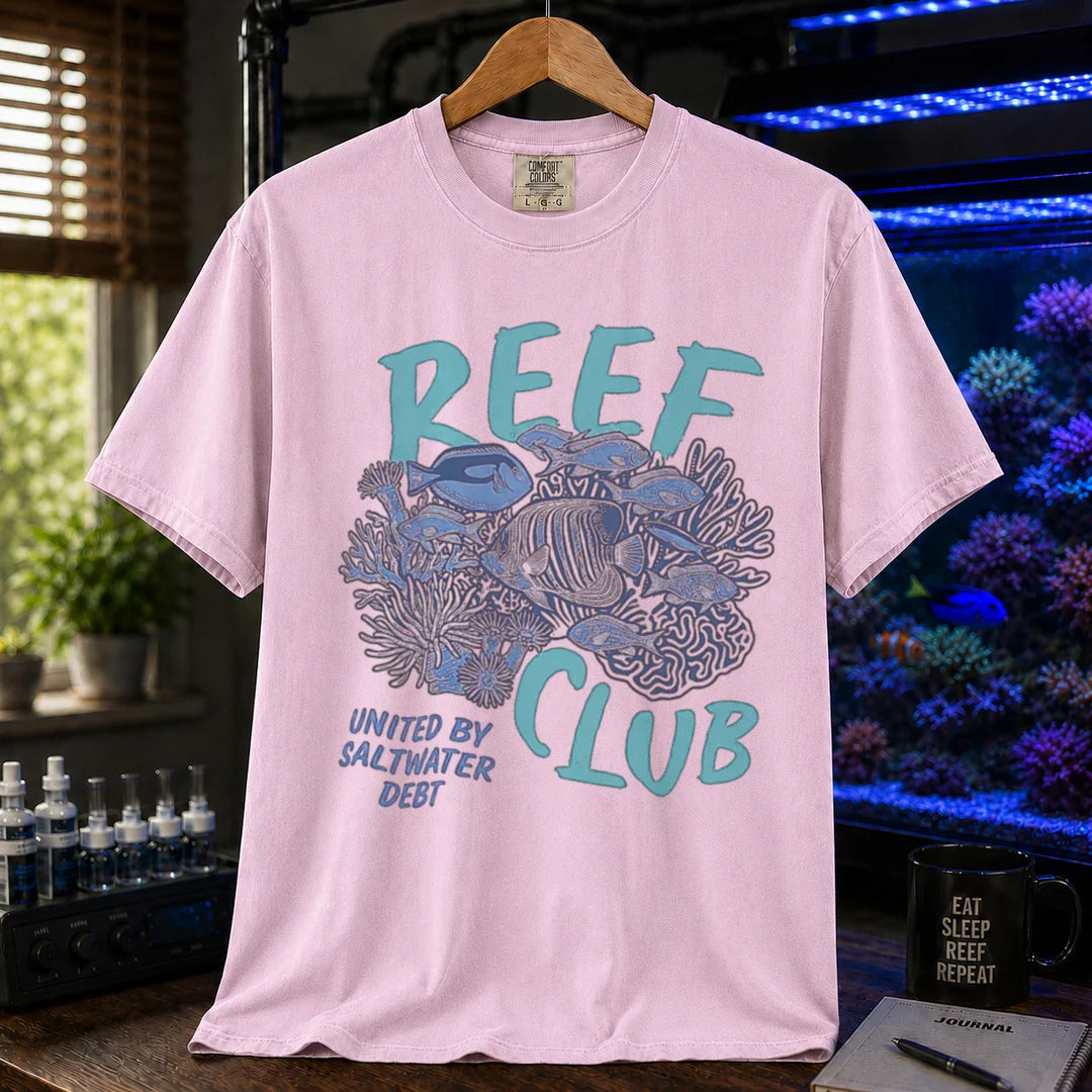 Saltwater aquarium graphic t-shirt featuring a detailed reef and fish illustration with text: REEF CLUB UNITED BY SALTWATER DEBT, pink crew neck tee