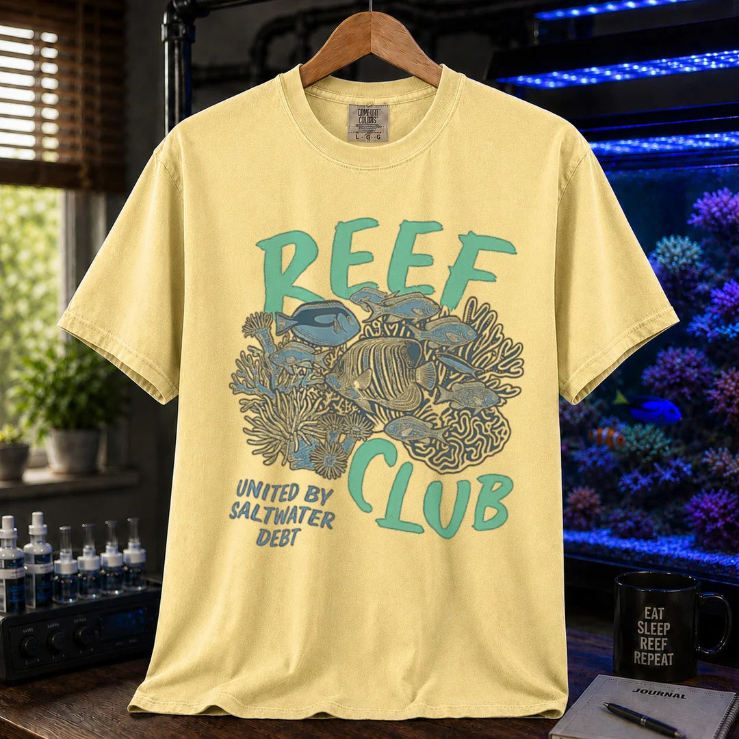 Saltwater aquarium graphic t-shirt featuring a detailed reef and fish illustration with text: REEF CLUB UNITED BY SALTWATER DEBT, yellow crew neck tee