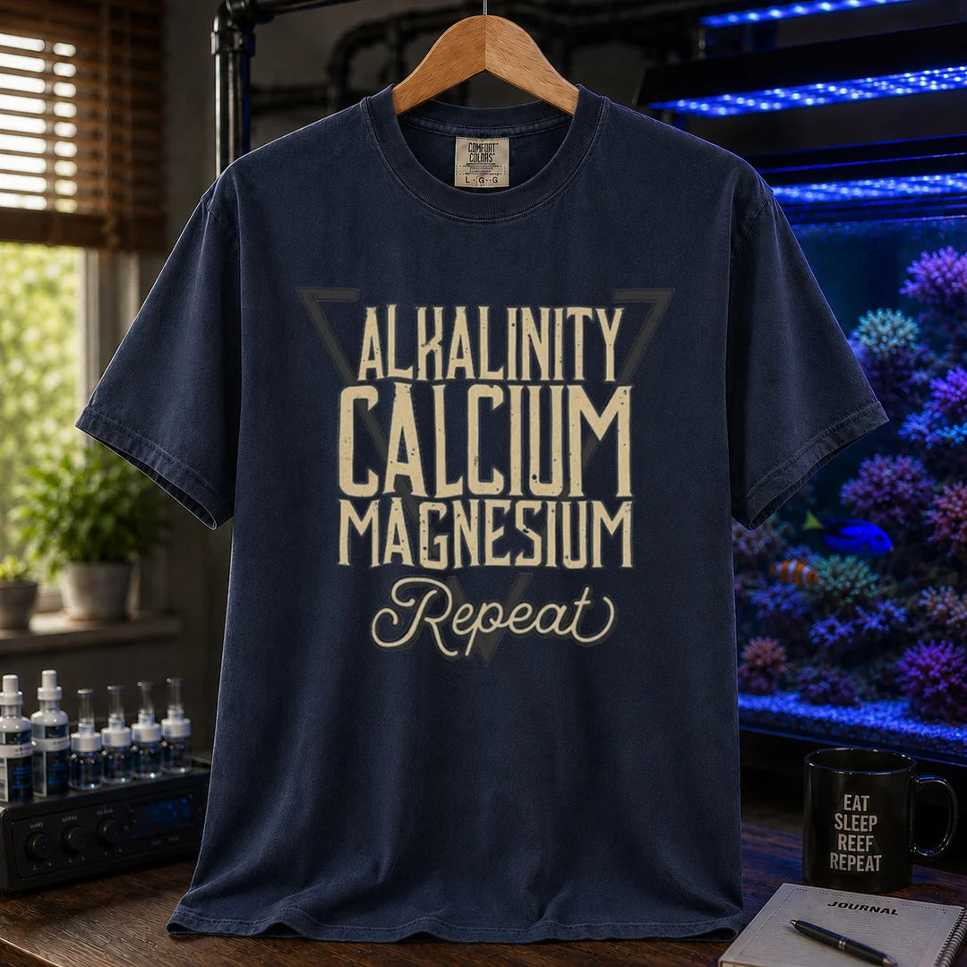 Saltwater aquarium graphic t-shirt featuring a triangle frame and text: ALKALINITY CALCIUM MAGNESIUM Repeat, navy crew neck tee