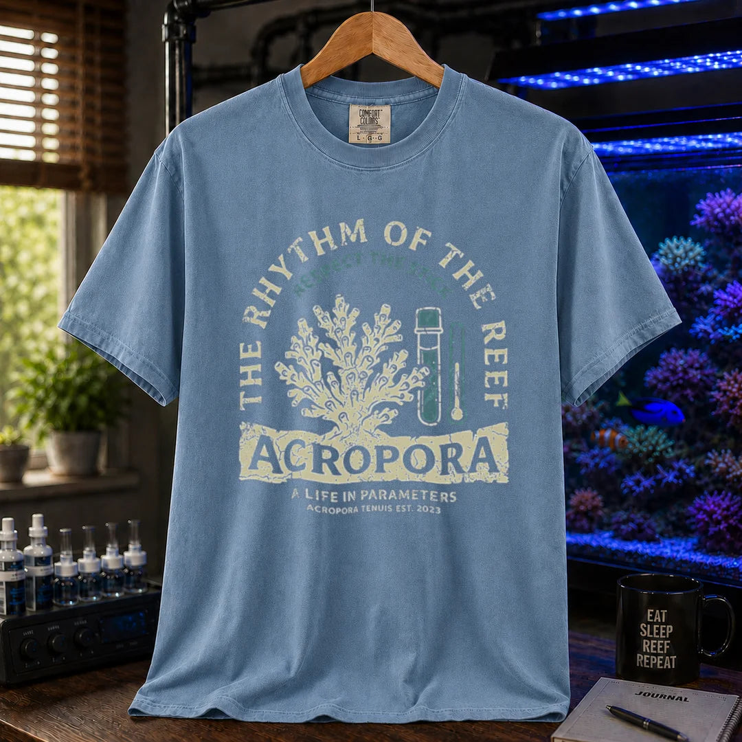 Saltwater aquarium graphic t-shirt featuring an Acropora coral and test kit illustration with text: THE RHYTHM OF THE REEF ACROPORA A LIFE IN PARAMETERS, blue crew neck tee