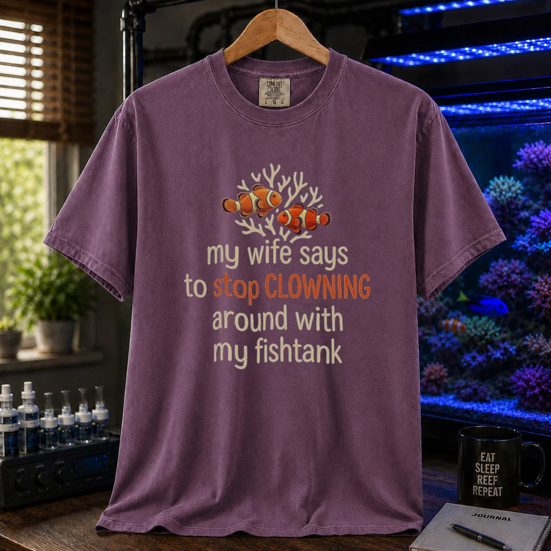 Saltwater aquarium graphic t-shirt featuring a clownfish illustration and text: my wife says to stop CLOWNING around with my fishtank, purple crew neck tee