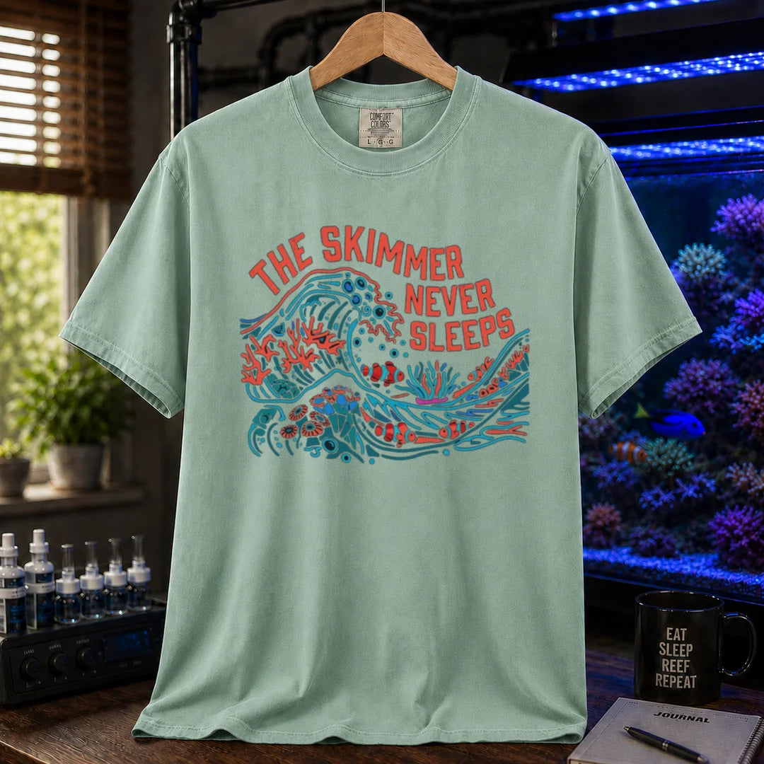 Saltwater aquarium graphic t-shirt featuring a colorful wave and reef illustration with text: THE SKIMMER NEVER SLEEPS, green crew neck tee