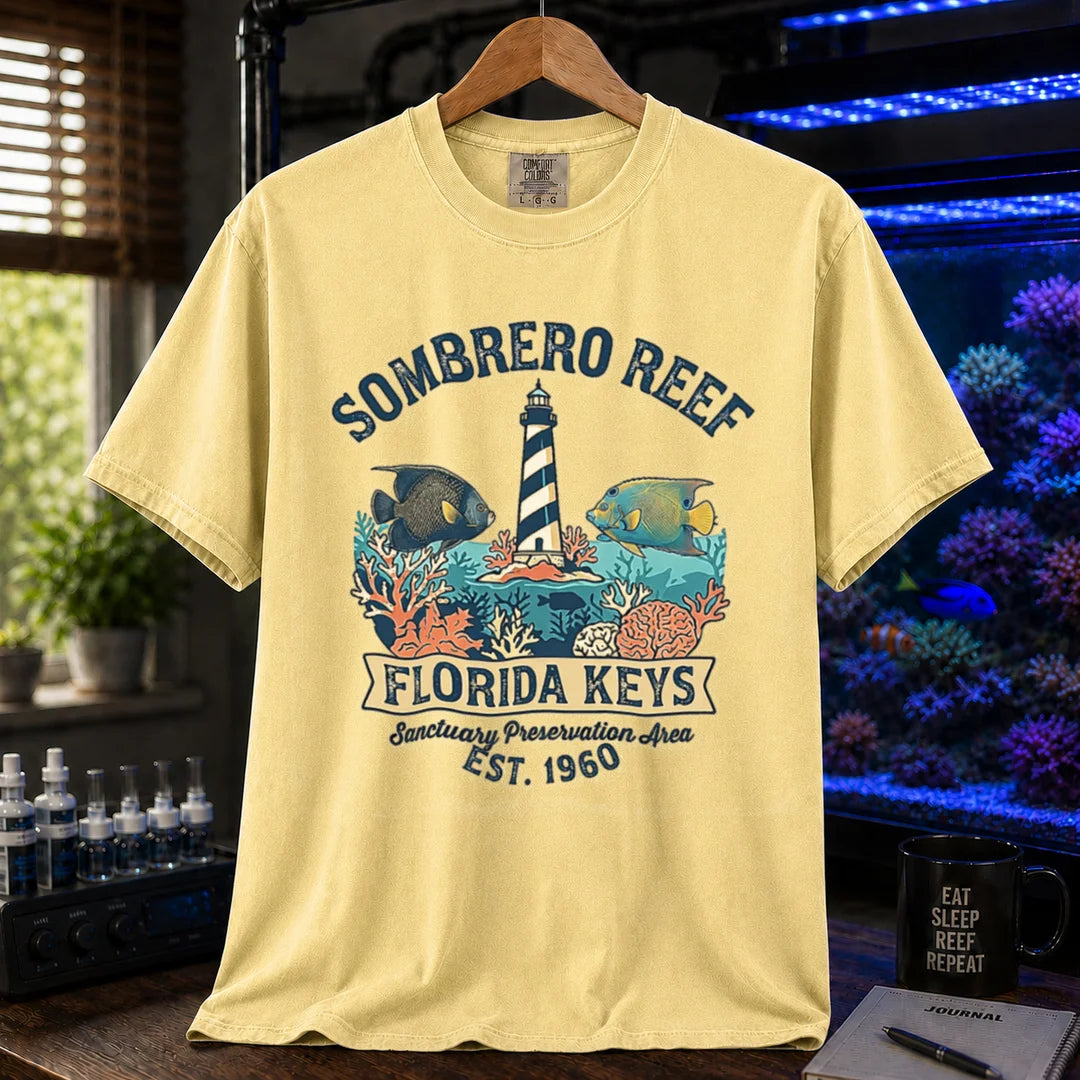 Saltwater aquarium graphic t-shirt featuring a lighthouse illustration, marine fish, and text: SOMBRERO REEF FLORIDA KEYS Sanctuary Preservation Area EST. 1960, yellow crew neck tee