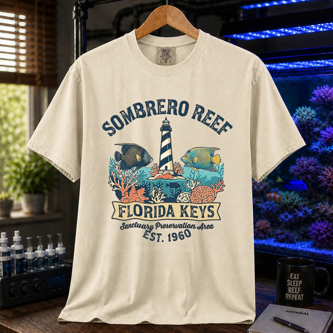 Saltwater aquarium graphic t-shirt featuring a lighthouse illustration, marine fish, and text: SOMBRERO REEF FLORIDA KEYS Sanctuary Preservation Area EST. 1960, cream, beige, ivory crew neck tee