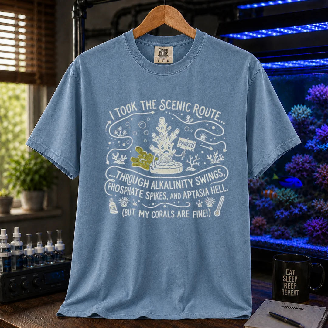 Saltwater aquarium graphic t-shirt featuring an illustrative map design with a coral character and text: I TOOK THE SCENIC ROUTE... THROUGH ALKALINITY SWINGS, PHOSPHATE SPIKES, AND APTASIA HELL. (BUT MY CORALS ARE FINE!), blue crew neck tee