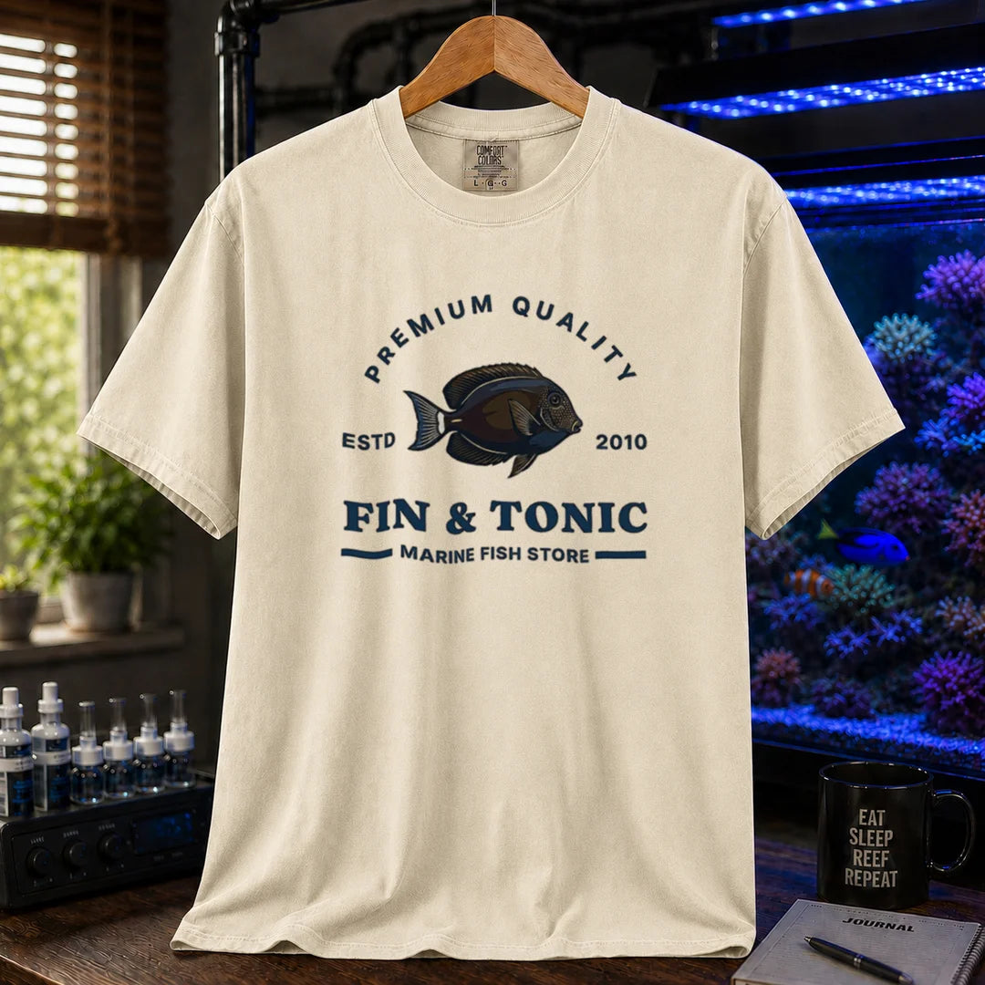 Saltwater aquarium graphic t-shirt featuring a marine fish badge design and text: PREMIUM QUALITY ESTD 2010 FIN & TONIC MARINE FISH STORE, cream, beige, ivory crew neck tee