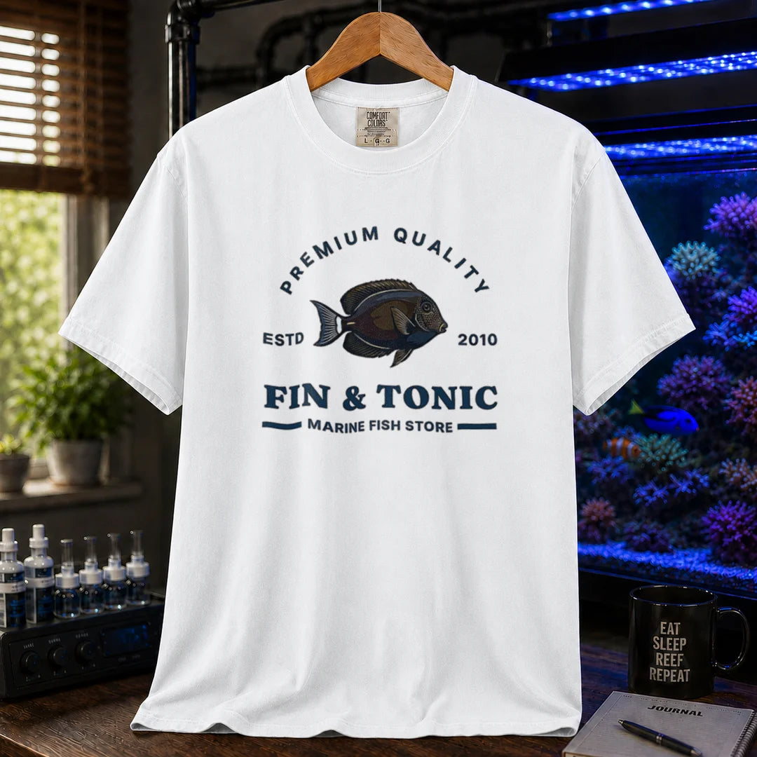 Saltwater aquarium graphic t-shirt featuring a marine fish badge design and text: PREMIUM QUALITY ESTD 2010 FIN & TONIC MARINE FISH STORE, white crew neck tee
