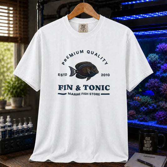 Saltwater aquarium graphic t-shirt featuring a marine fish badge design and text: PREMIUM QUALITY ESTD 2010 FIN & TONIC MARINE FISH STORE, white crew neck tee