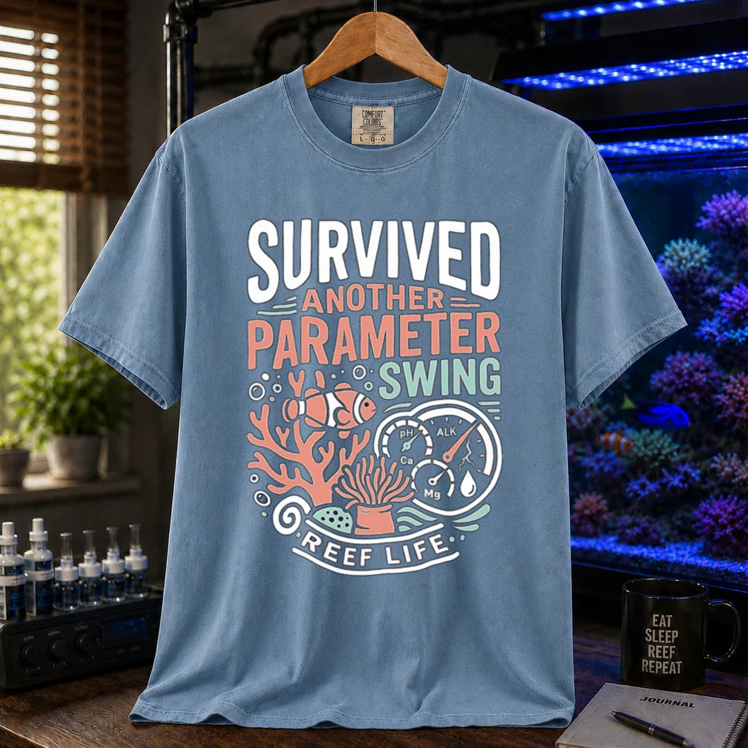 Saltwater aquarium graphic t-shirt featuring a clownfish, coral, parameter gauges, and text: SURVIVED ANOTHER PARAMETER SWING REEF LIFE, blue crew neck tee