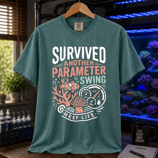 Saltwater aquarium graphic t-shirt featuring a clownfish, coral, parameter gauges, and text: SURVIVED ANOTHER PARAMETER SWING REEF LIFE, green crew neck tee
