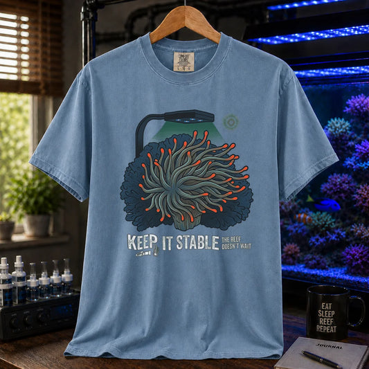Saltwater aquarium graphic t-shirt featuring an anemone illustration under a reef light and text: KEEP IT STABLE THE REEF DOESN'T WAIT, blue crew neck tee