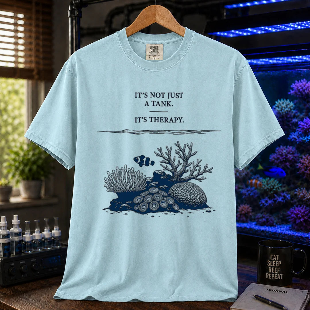 Saltwater aquarium graphic t-shirt featuring an underwater reef scene with a clownfish and text: IT'S NOT JUST A TANK. IT'S THERAPY., light blue crew neck tee