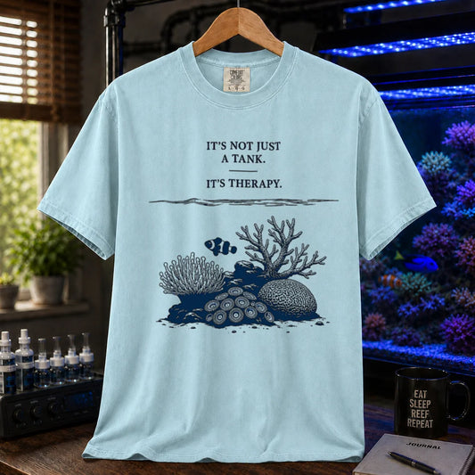 Saltwater aquarium graphic t-shirt featuring an underwater reef scene with a clownfish and text: IT'S NOT JUST A TANK. IT'S THERAPY., light blue crew neck tee