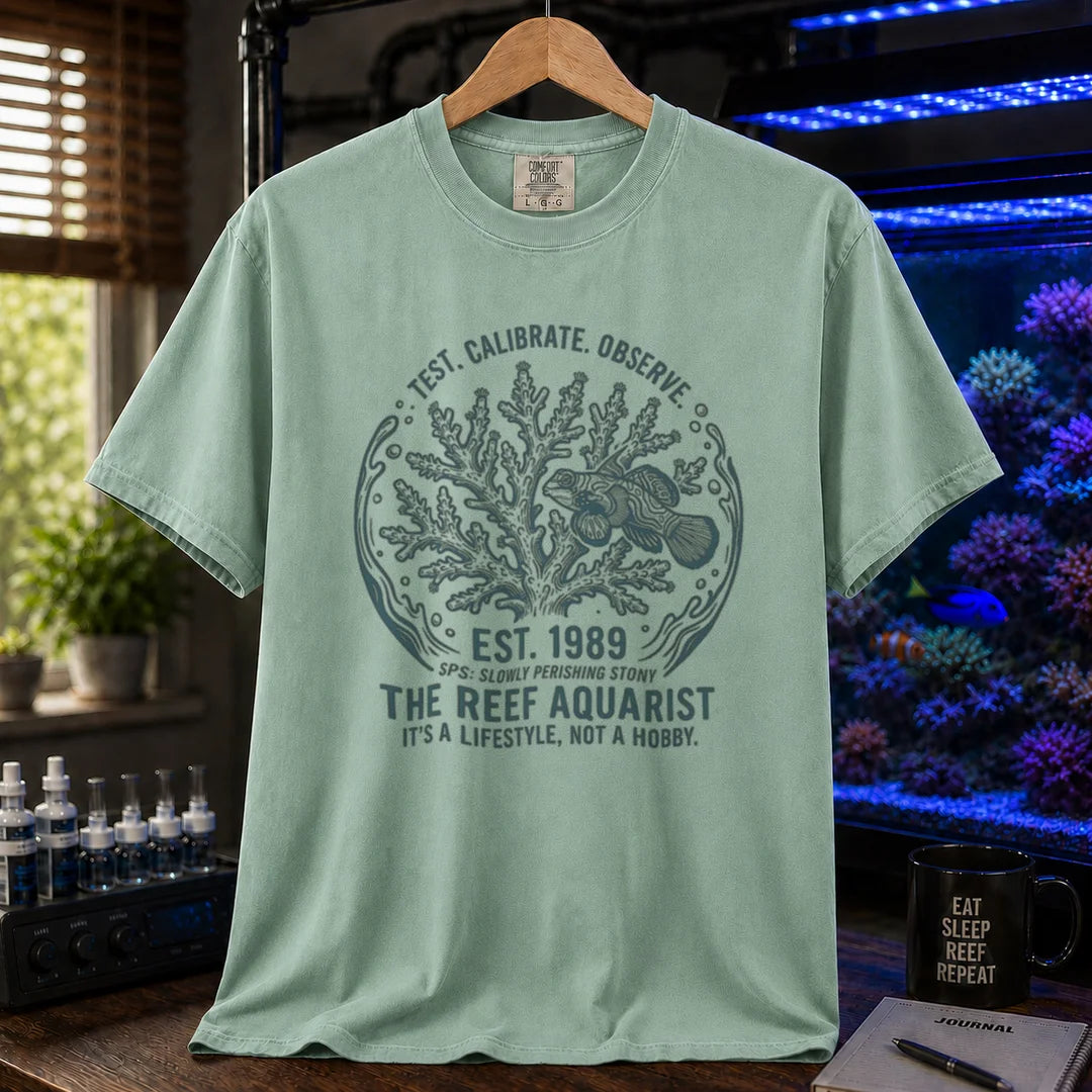 Saltwater aquarium graphic t-shirt featuring a circular coral and fish badge with text: TEST. CALIBRATE. OBSERVE. EST. 1989 THE REEF AQUARIST IT'S A LIFESTYLE, NOT A HOBBY., green crew neck tee