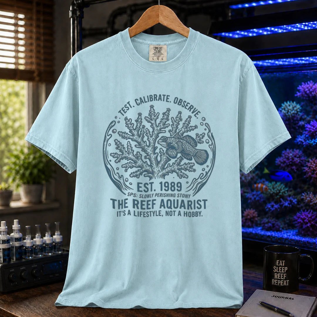 Saltwater aquarium graphic t-shirt featuring a circular coral and fish badge with text: TEST. CALIBRATE. OBSERVE. EST. 1989 THE REEF AQUARIST IT'S A LIFESTYLE, NOT A HOBBY., light blue crew neck tee