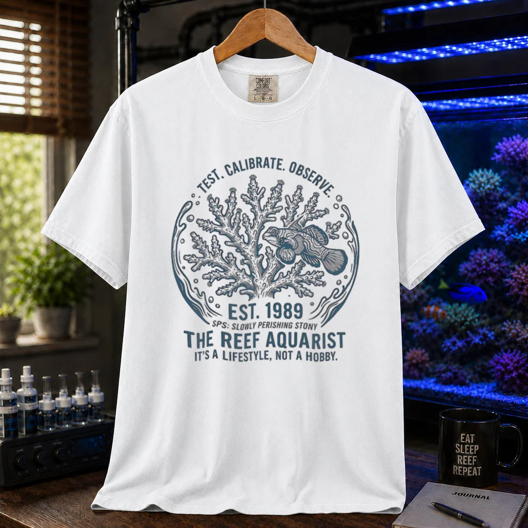Saltwater aquarium graphic t-shirt featuring a circular coral and fish badge with text: TEST. CALIBRATE. OBSERVE. EST. 1989 THE REEF AQUARIST IT'S A LIFESTYLE, NOT A HOBBY., white crew neck tee