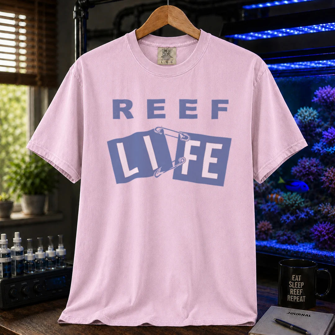 Saltwater aquarium graphic t-shirt featuring blue text reading REEF LIFE with safety pins holding the word LIFE together, pink crew neck tee