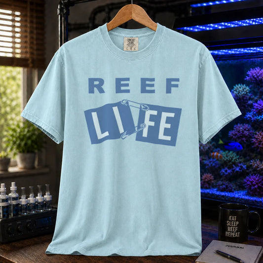 Saltwater aquarium graphic t-shirt featuring blue text reading REEF LIFE with safety pins holding the word LIFE together, blue crew neck tee