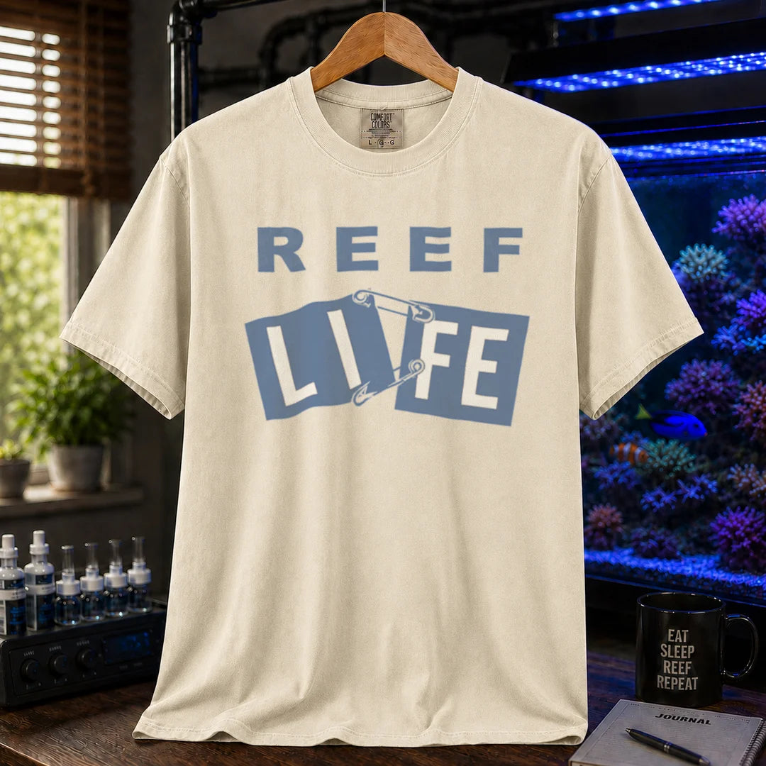 Saltwater aquarium graphic t-shirt featuring blue text reading REEF LIFE with safety pins holding the word LIFE together, cream, beige, ivory crew neck tee