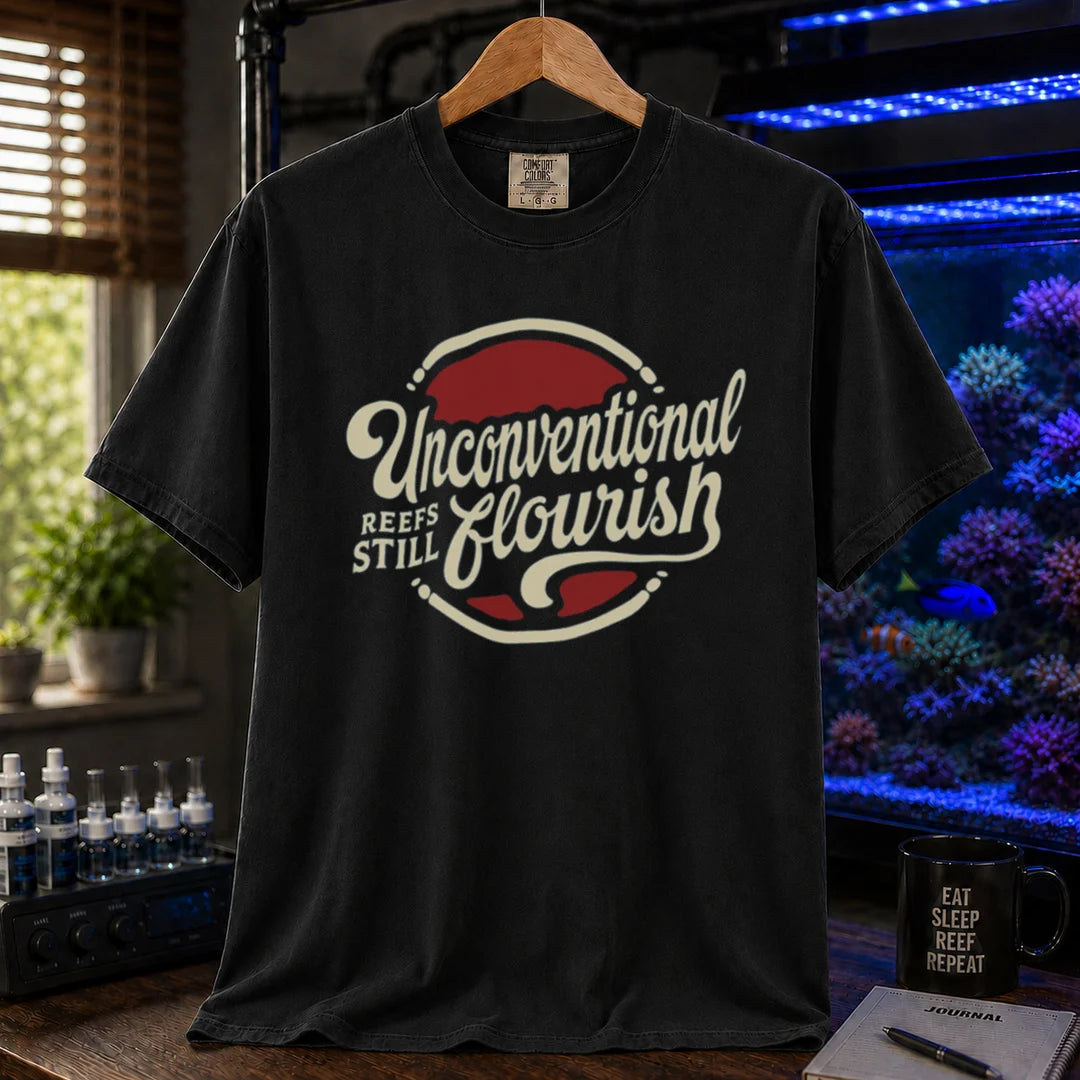 Saltwater aquarium graphic t-shirt featuring a retro red and blue badge with cream typography reading Unconventional Reefs Still Flourish, black crew neck tee