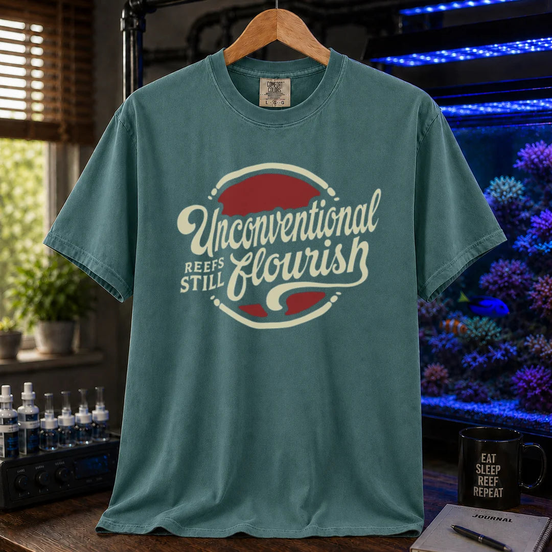 Saltwater aquarium graphic t-shirt featuring a retro red and blue badge with cream typography reading Unconventional Reefs Still Flourish, green crew neck tee