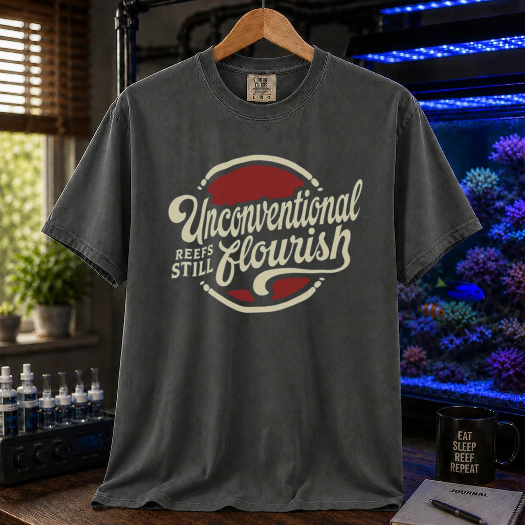 Saltwater aquarium graphic t-shirt featuring a retro red and blue badge with cream typography reading Unconventional Reefs Still Flourish, dark grey crew neck tee