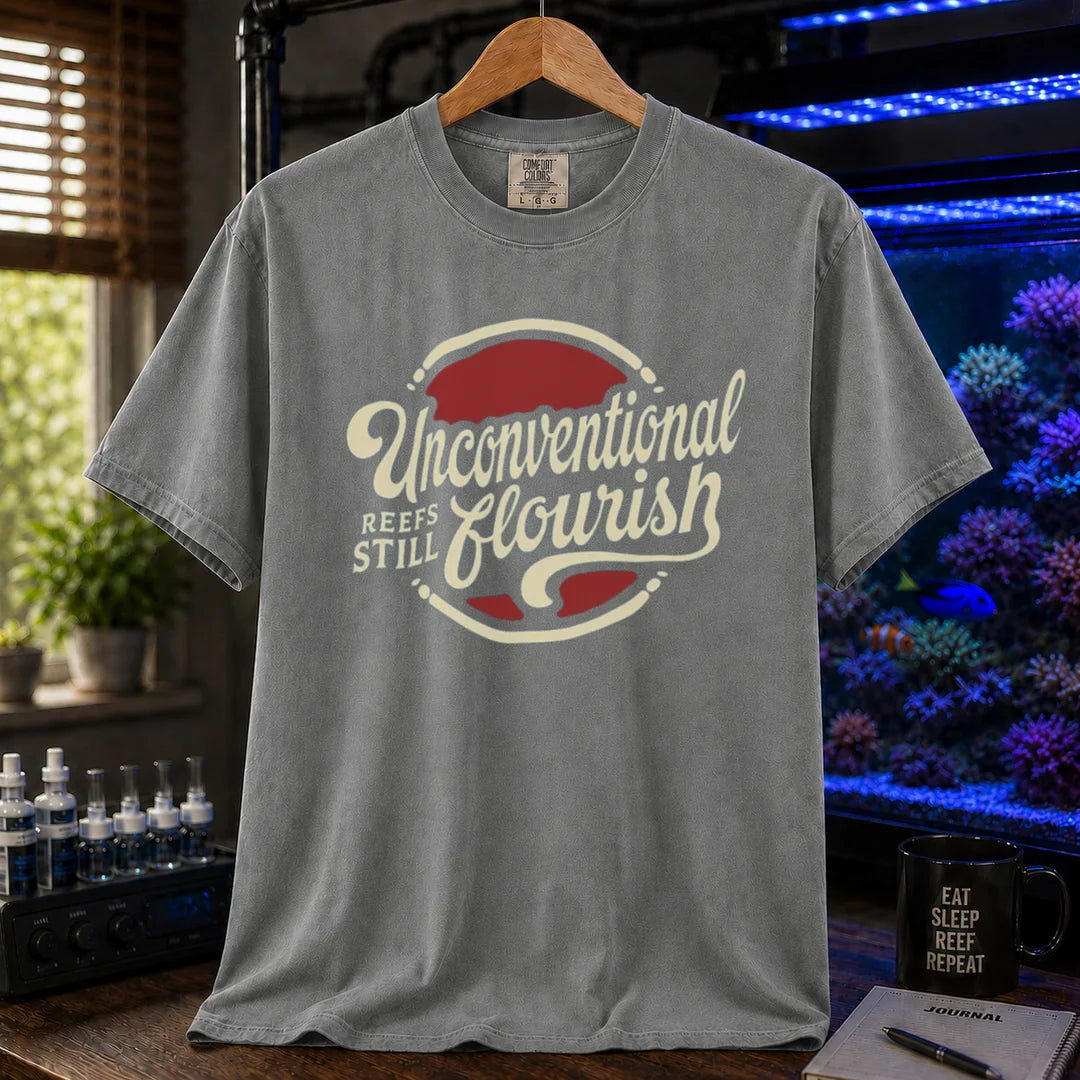 Saltwater aquarium graphic t-shirt featuring a retro red and blue badge with cream typography reading Unconventional Reefs Still Flourish, grey crew neck tee