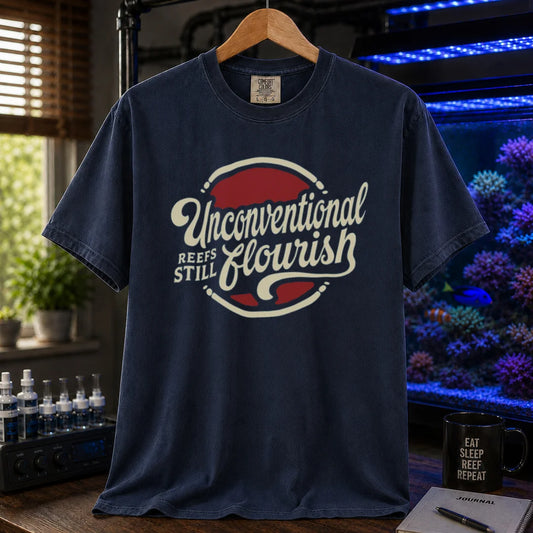 Saltwater aquarium graphic t-shirt featuring a retro red and blue badge with cream typography reading Unconventional Reefs Still Flourish, navy crew neck tee
