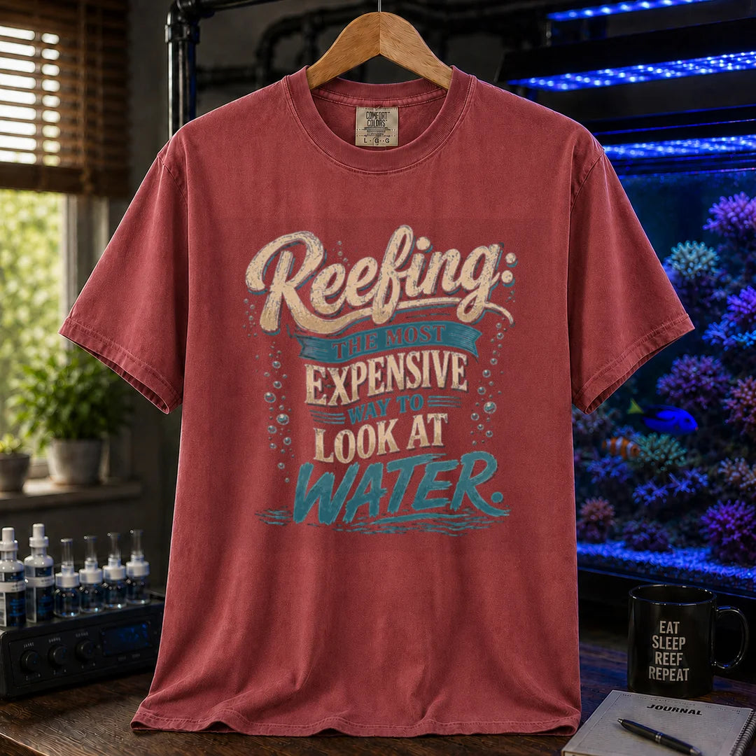 Saltwater aquarium graphic t-shirt featuring cream and blue typography reading Reefing: The Most Expensive Way To Look At Water with bubble accents, maroon, red crew neck tee