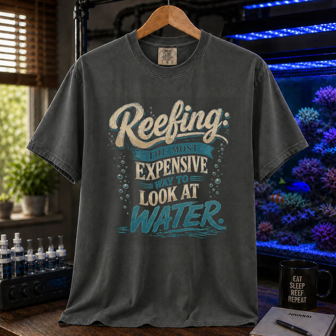 Saltwater aquarium graphic t-shirt featuring cream and blue typography reading Reefing: The Most Expensive Way To Look At Water with bubble accents, dark grey crew neck tee
