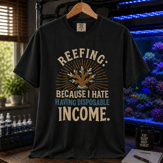 Saltwater aquarium graphic t-shirt featuring distressed cream and blue typography reading Reefing: Because I Hate Having Disposable Income with a coral illustration and sunburst background, black crew neck tee