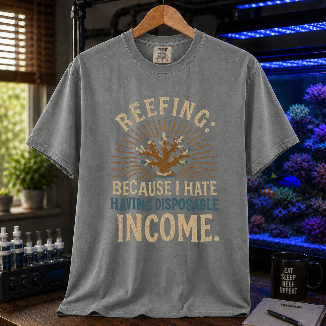 Saltwater aquarium graphic t-shirt featuring distressed cream and blue typography reading Reefing: Because I Hate Having Disposable Income with a coral illustration and sunburst background, grey crew neck tee