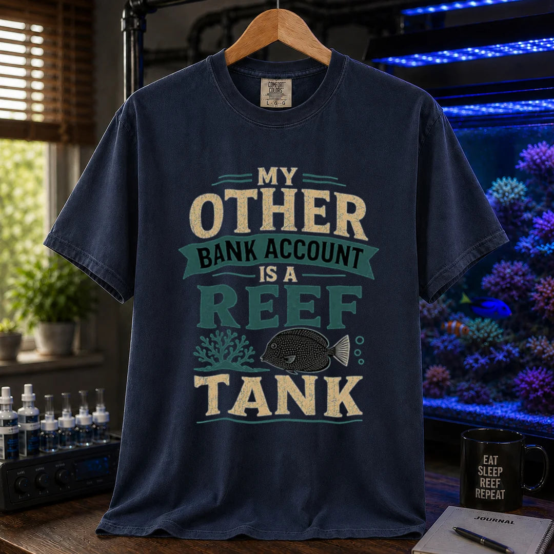 Saltwater aquarium graphic t-shirt featuring cream and teal distressed typography reading My Other Bank Account Is A Reef Tank with coral and tang illustrations, navy crew neck tee